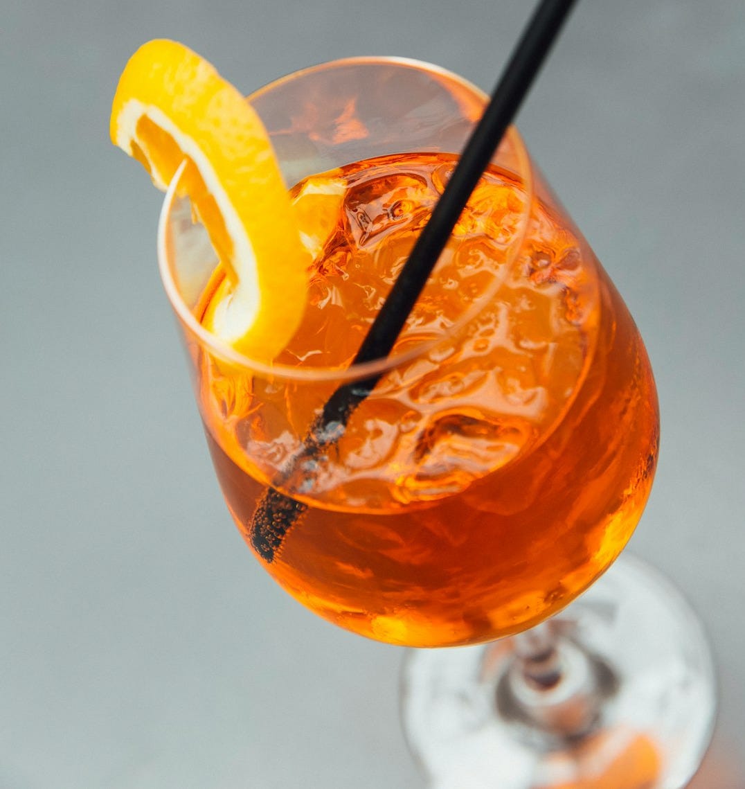 3/4 filled long-stem glass cup with straw and slice of orange 3/4 filled long-stem glass cup with straw and slice of orange
