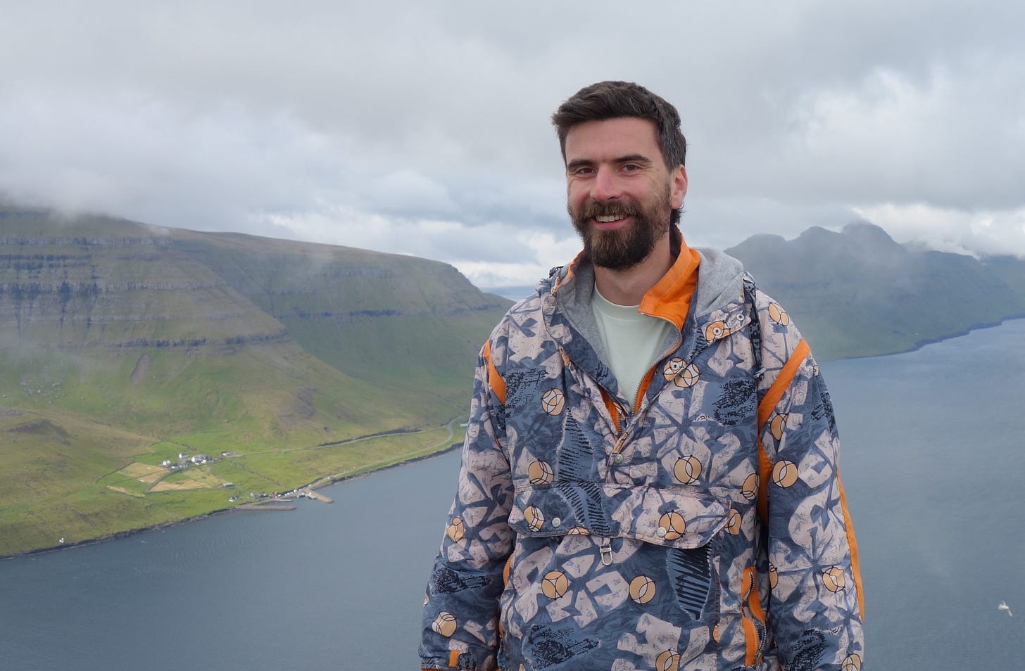 Zac Crellin, creator of Open Newswire stands smiling in front of a natural landscape.
