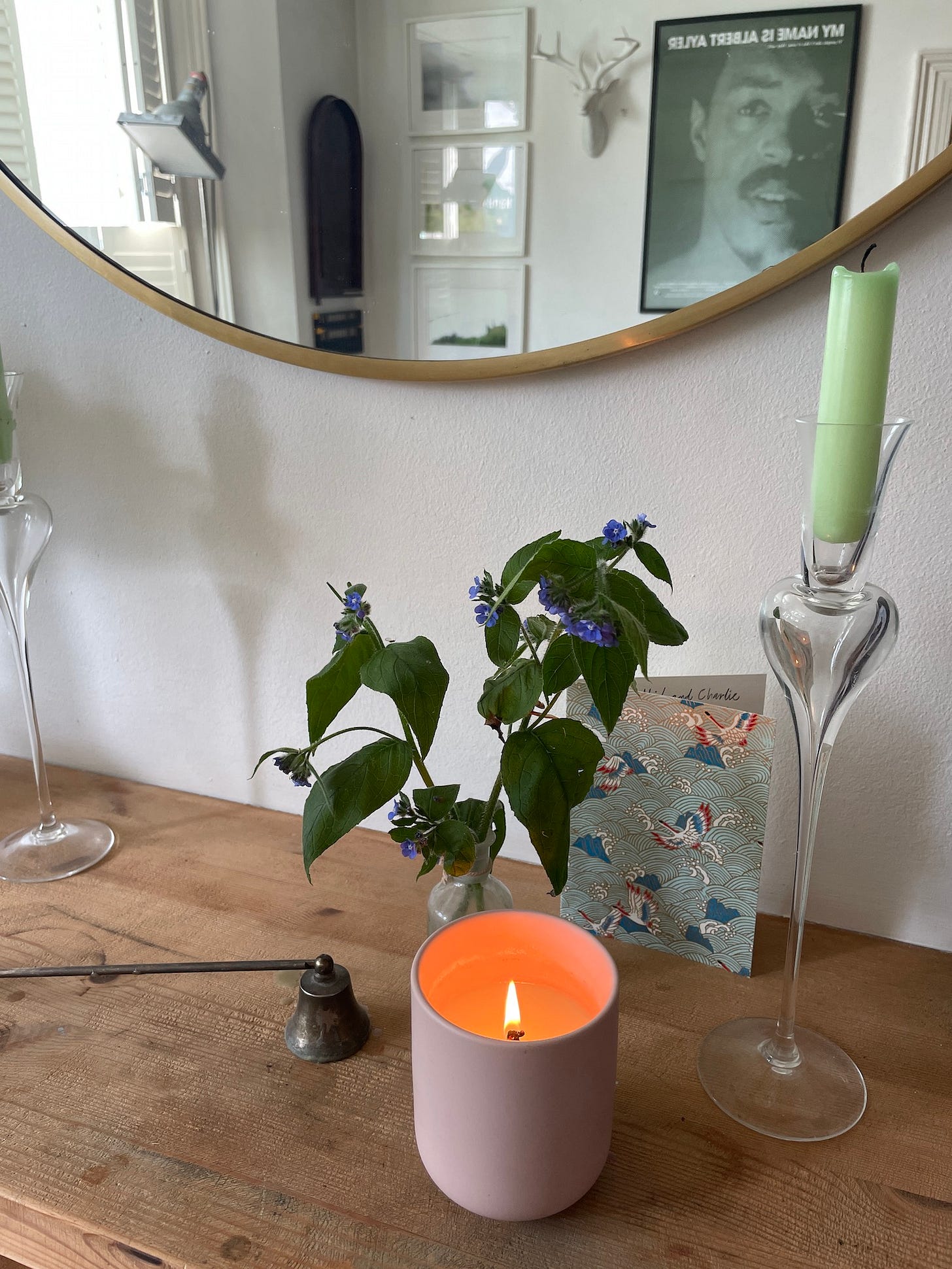 mantlepiece with lit candle and flowers and brass mirror above