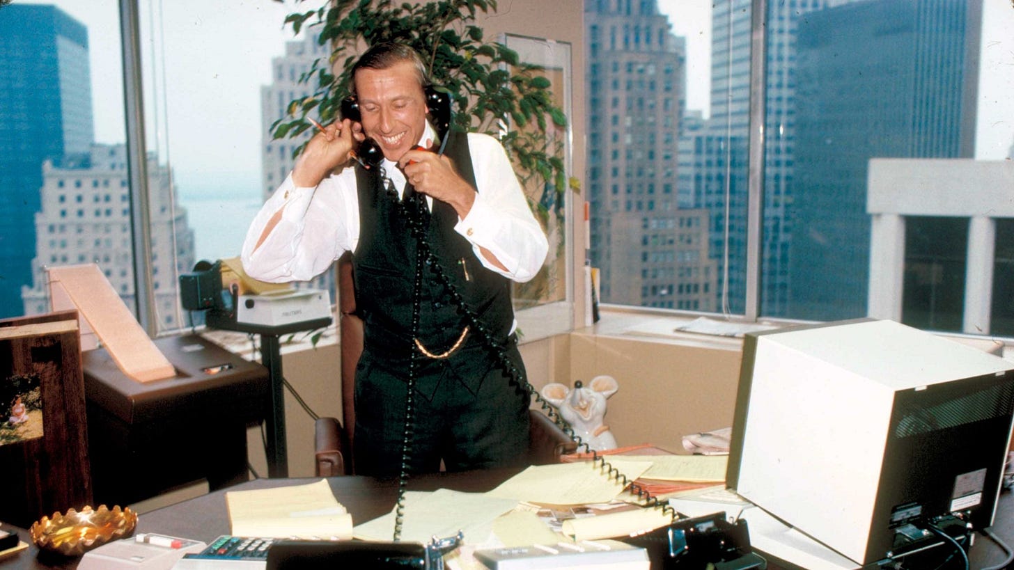 Ivan Boesky in an office holding two wired telephones