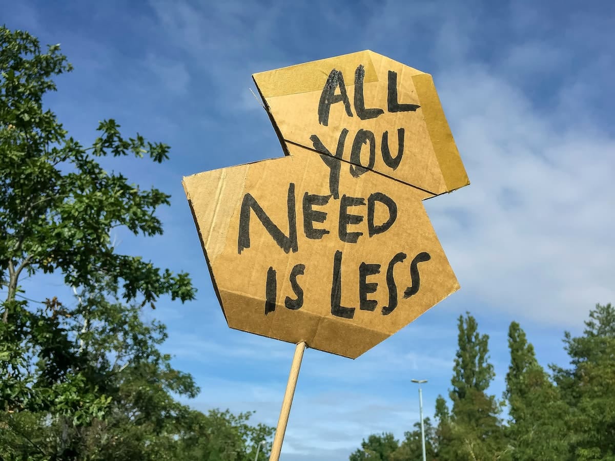 A cardboard protest banner saying All You Need Is Less A cardboard protest banner saying All You Need Is Less