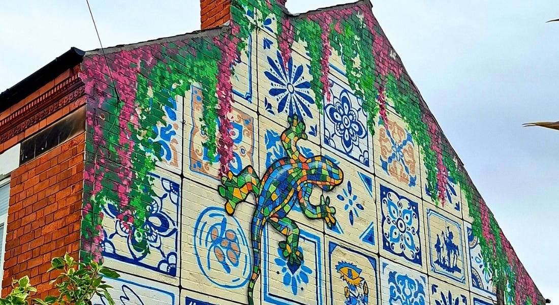 A house with a mural on it with blue and yellow flowers and a lizard A house with a mural on it with blue and yellow flowers and a lizard