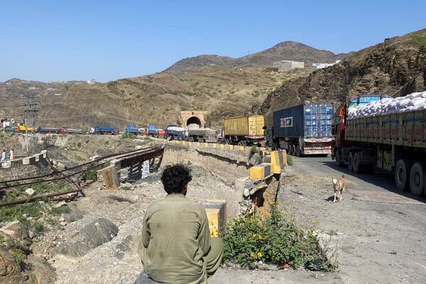 A long line of trucks sitting still on a mountainous road.
