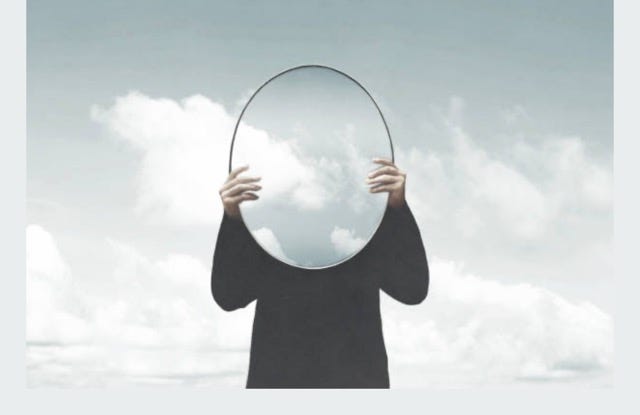 A person holding a mirror over their face

Description automatically generated
