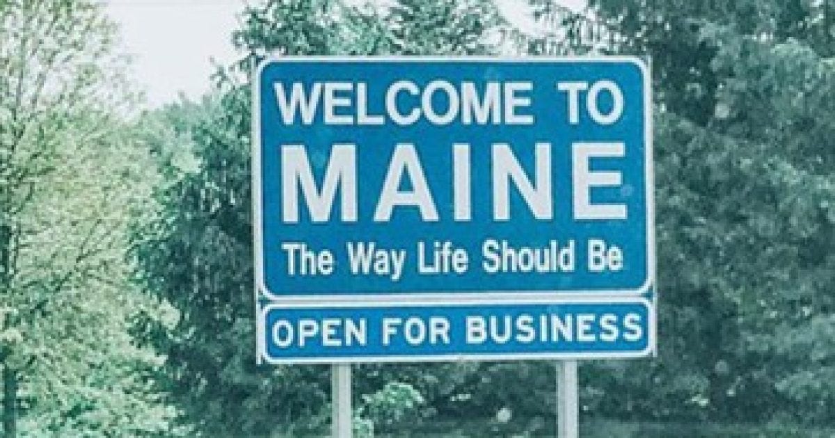 Welcome to Maine sign featuring the slogan "The Way Life Should Be" and indicating the state is open for business, surrounded by greenery. Welcome to Maine sign featuring the slogan "The Way Life Should Be" and indicating the state is open for business, surrounded by greenery.