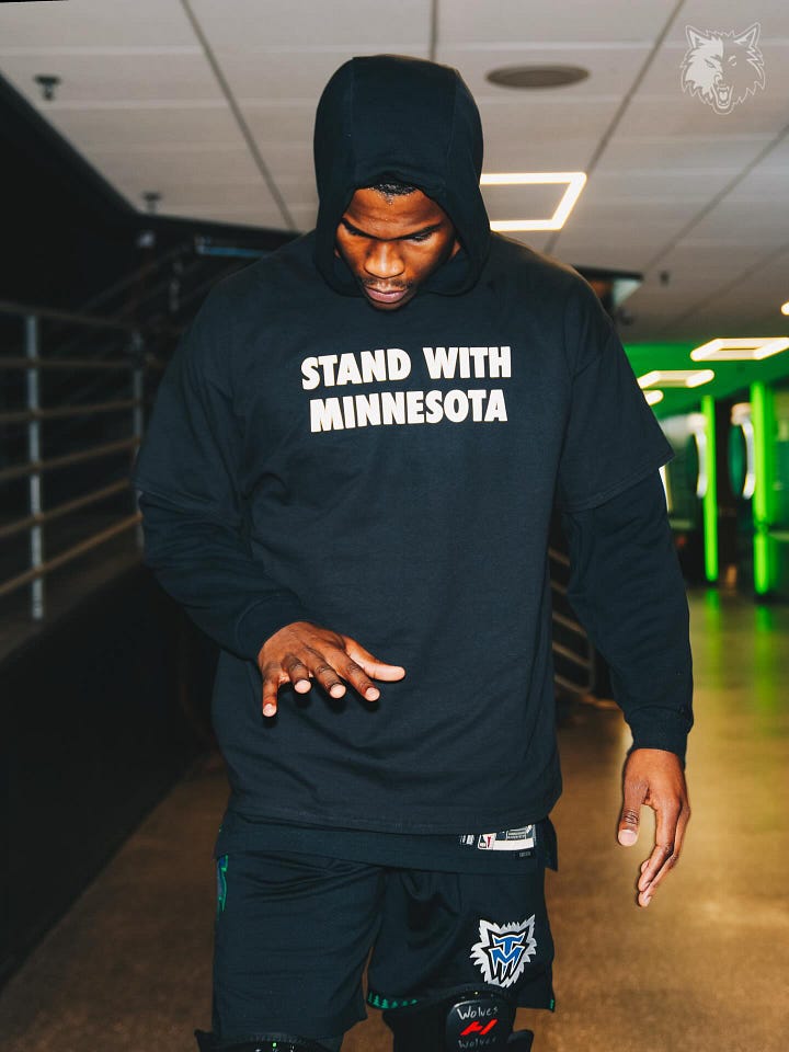 Very tall basketball players wearing black t-shirts that say Stand With Minnesota in white block letters