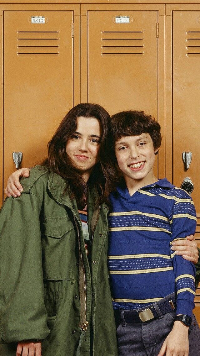 This may contain: two people standing next to each other in front of lockers