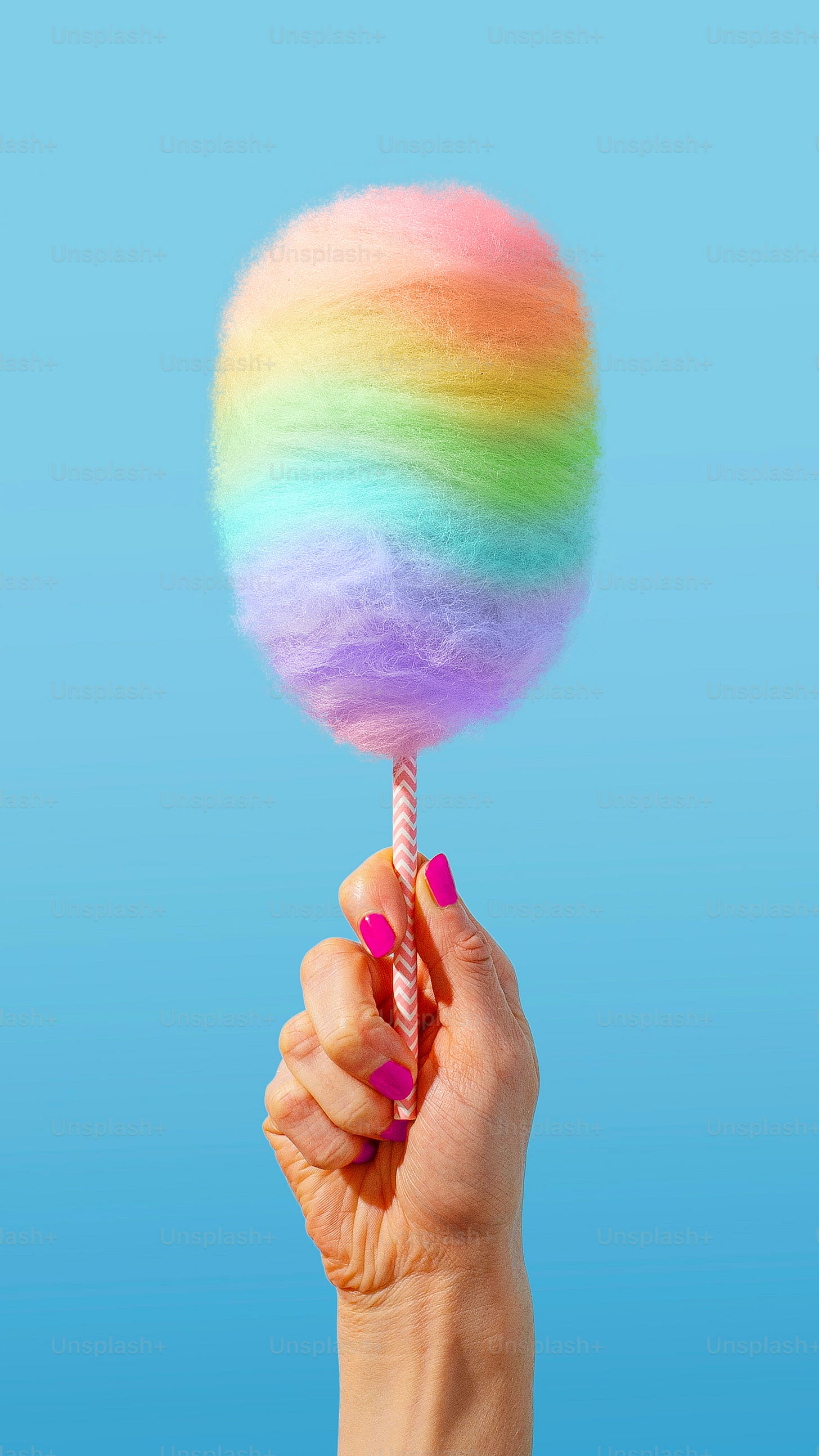 a hand holding a rainbow lollipop on a stick