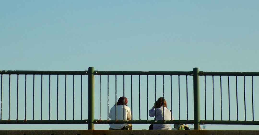 a couple of people sitting on top of a bridge
