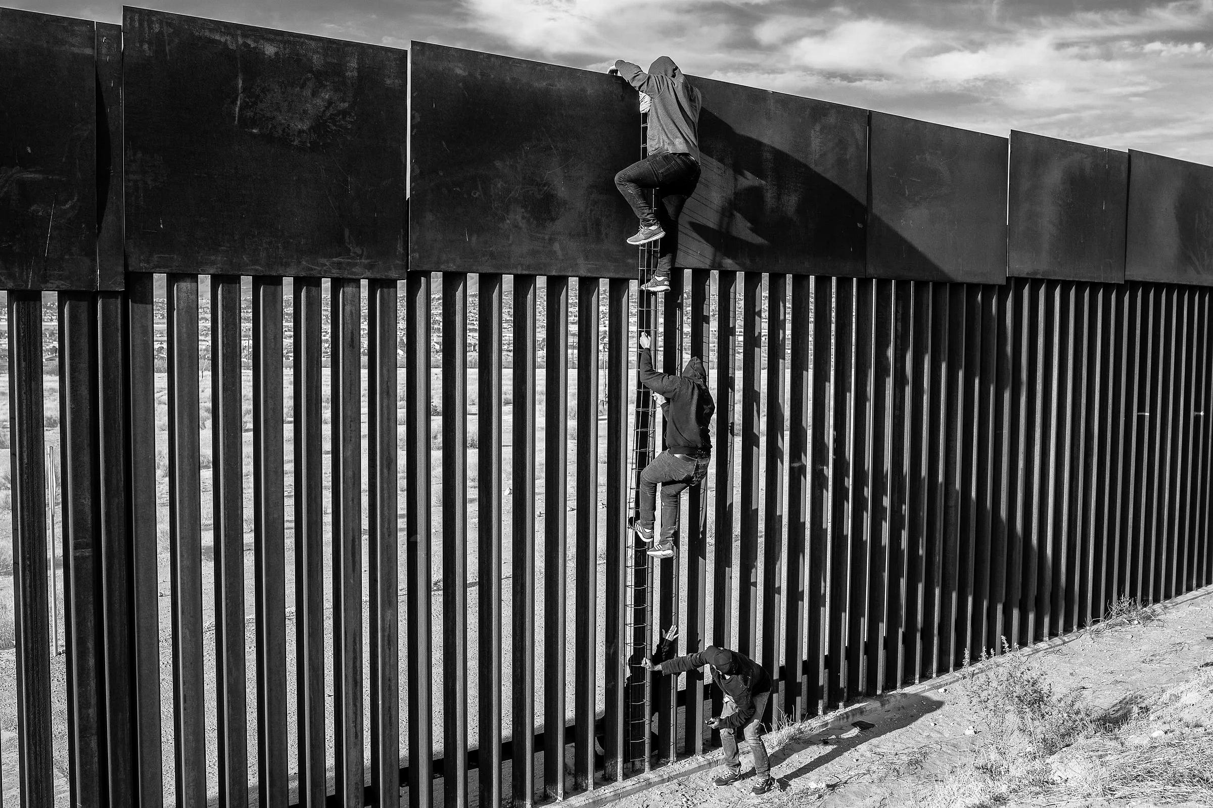 In Ciudad Juárez, migrants use a home-made ladder to climb a section of the border wall with the help of a smuggler, April 1, 2021 © Alejandro Cegarra