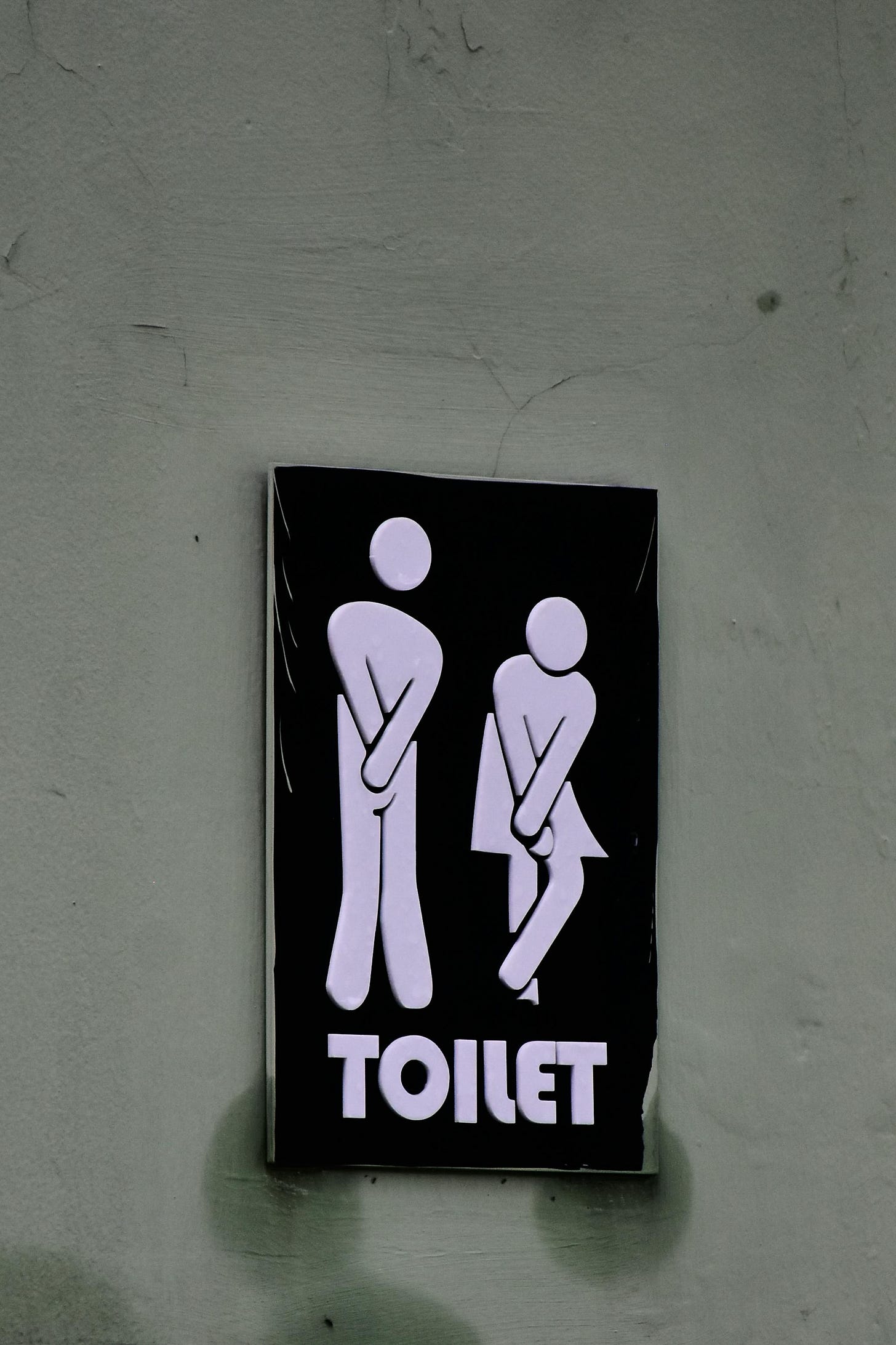 Photo of figures crossing their legs as a sign to a public restroom.