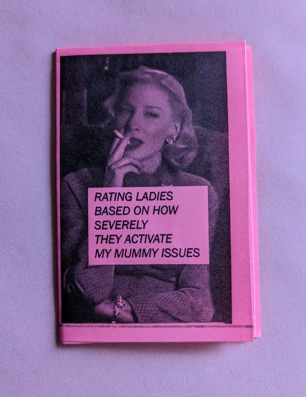 Pink zine on purple background, image of Cate Blanchett smoking in character in the movie Carol - the title text on the zine reads Rating ladies based on how severely they activate my mummy issues