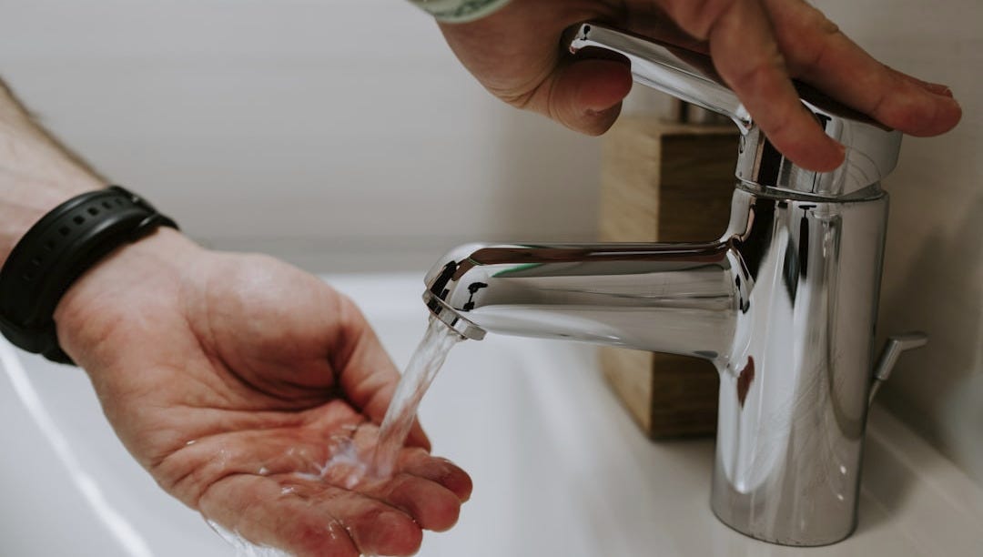 person holding stainless steel faucet