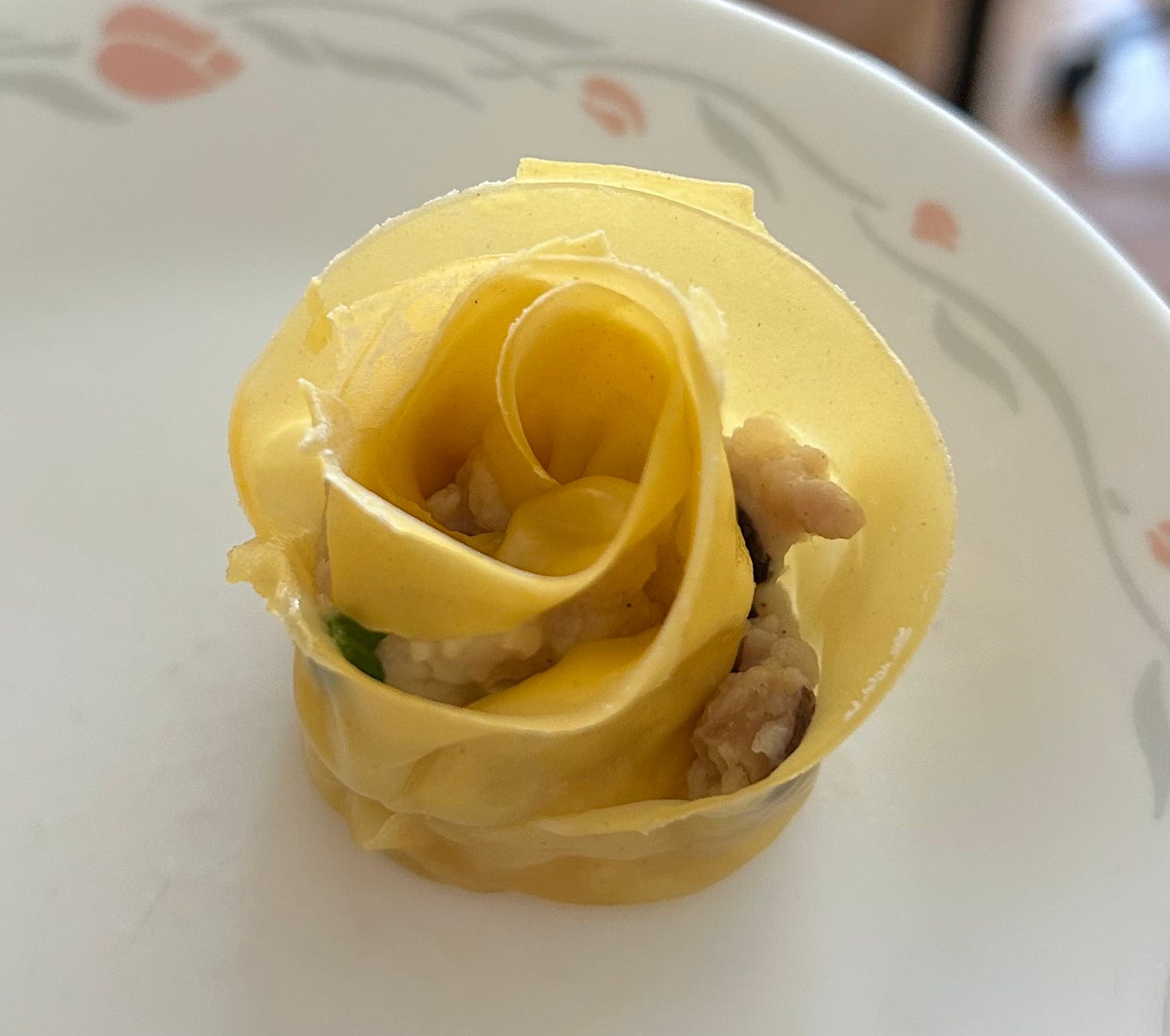 Siu mai with yellow, rose-like petals made from the wrapper dough on a white plate.