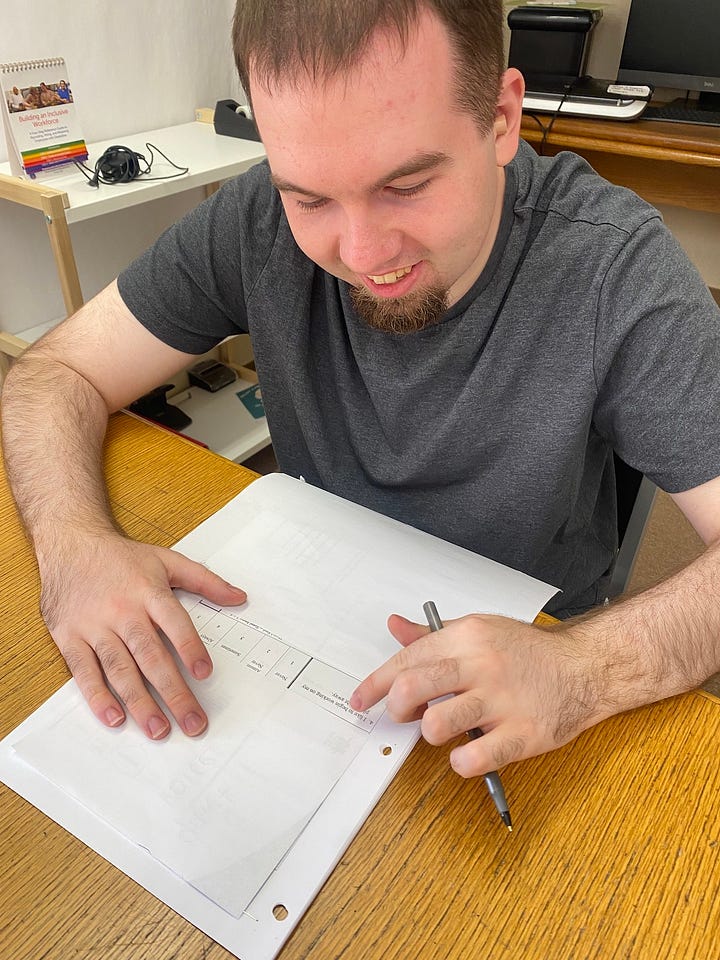 A young man writing on a worksheet at a table next to the Pathway to Work logo