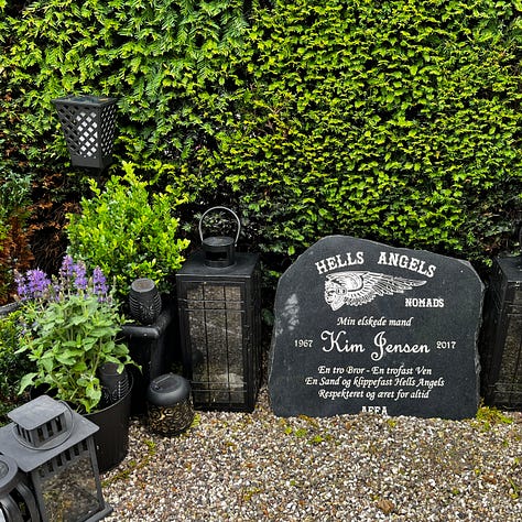 Tove Ditlevsen's simple stone, a battered folding chair leans next to an Arabic grave planted with flowers; Hells Angel gravestone with candle holder and plants