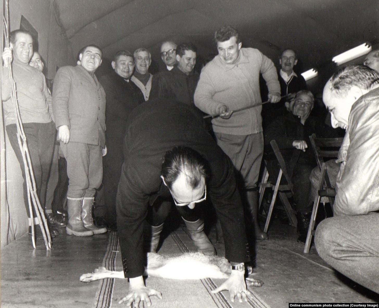 A Romanian diplomat is whipped on the backside by Ceausescu while crouching over the carcass of a hare. The photo was taken during a hunting trip with the heads of Romania’s diplomatic missions in 1969.