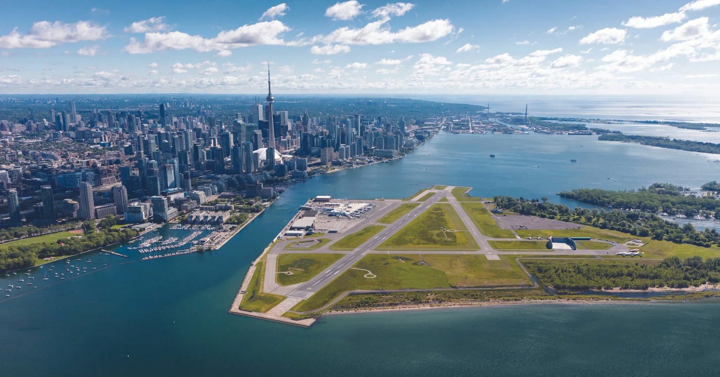 Aerial photograph of Billy Bishop Toronto City Airport as it currently exists on the Toronto Islands, with the runway ending at Lake Ontario's edge and the Toronto skyline rising behind it. Aerial photograph of Billy Bishop Toronto City Airport as it currently exists on the Toronto Islands, with the runway ending at Lake Ontario's edge and the Toronto skyline rising behind it.