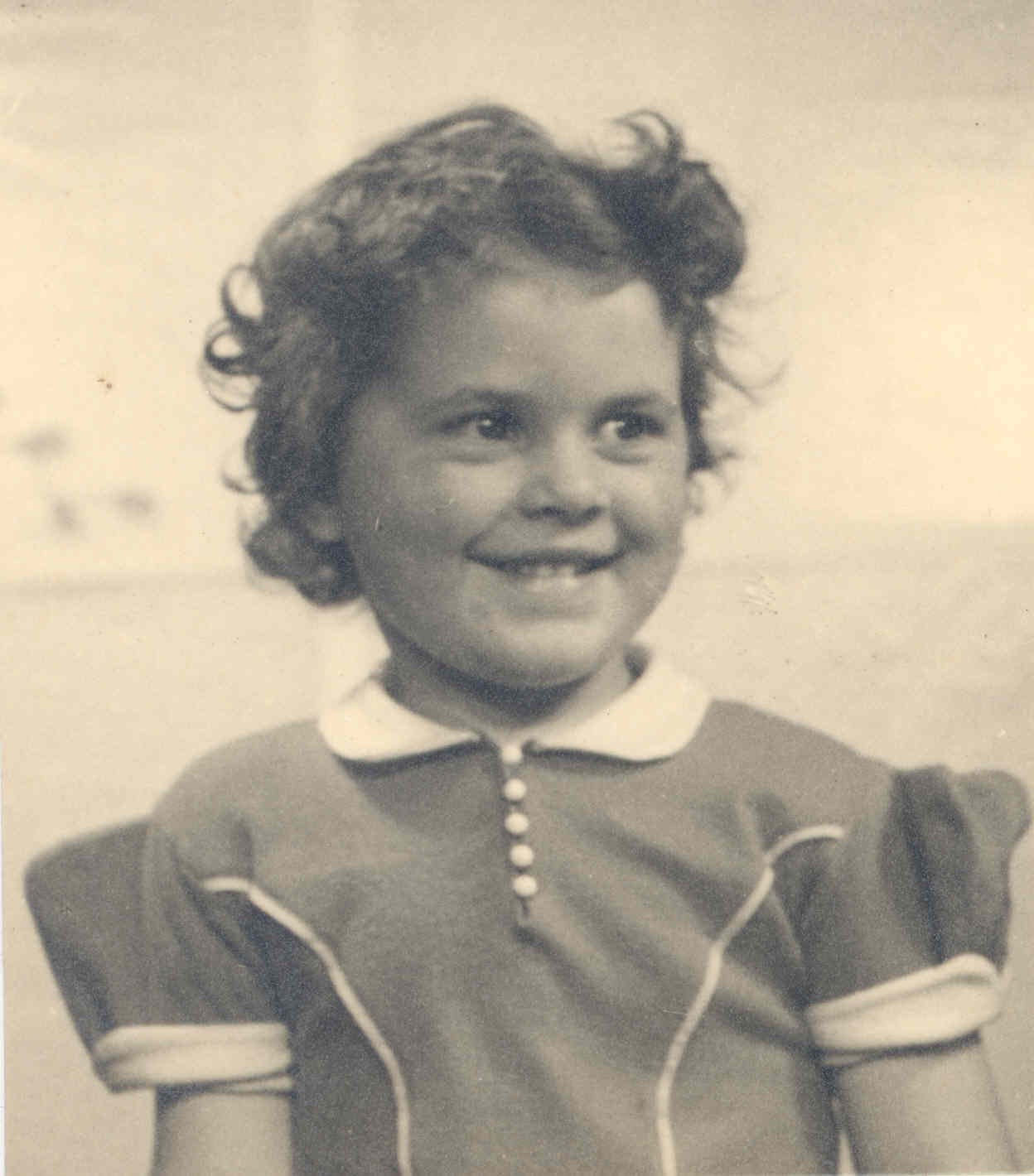 Judith as a young child, smiling and dressed in clothes of the era.
