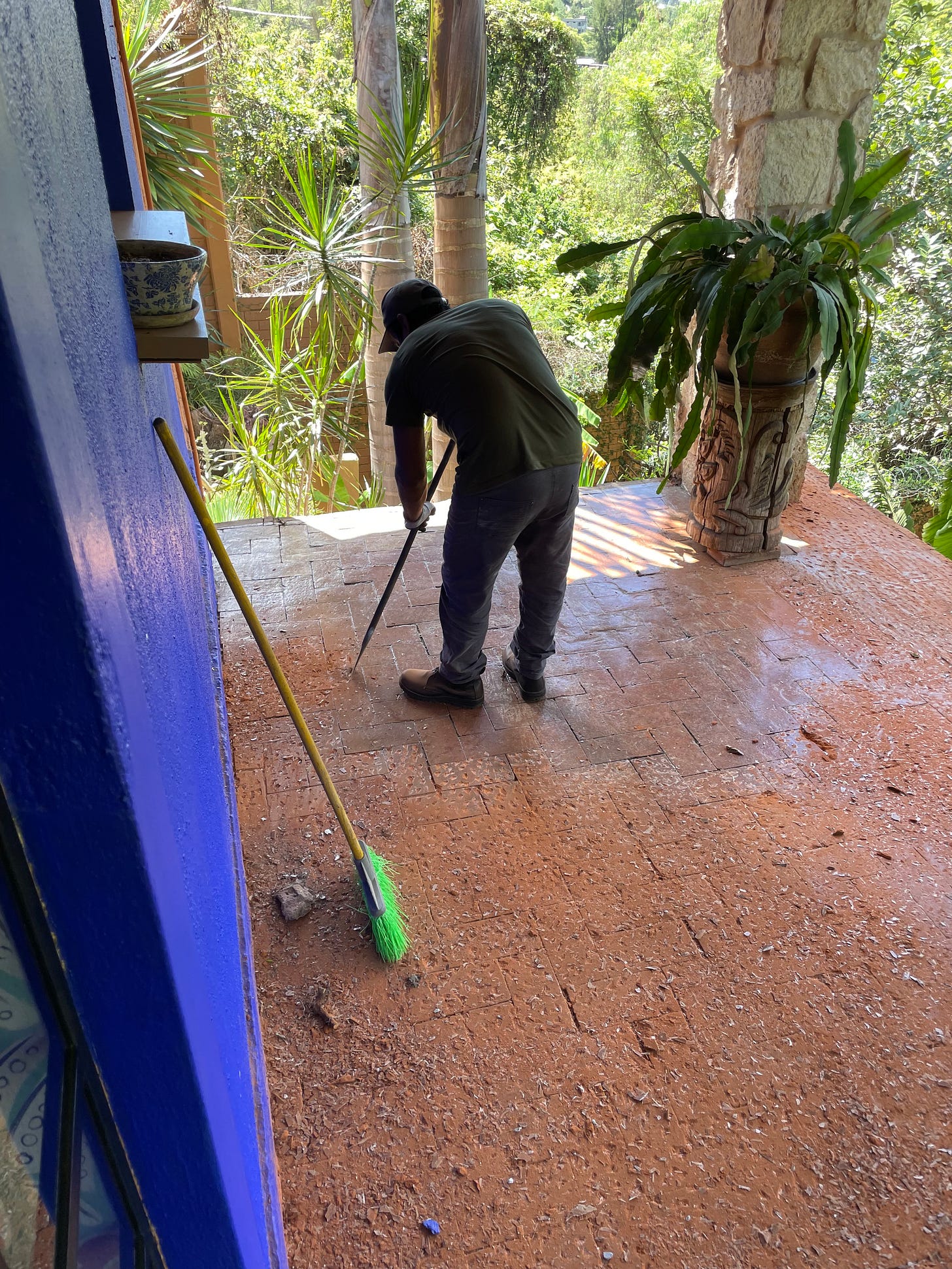 A man manually chipping a brick floor with a large chisel.