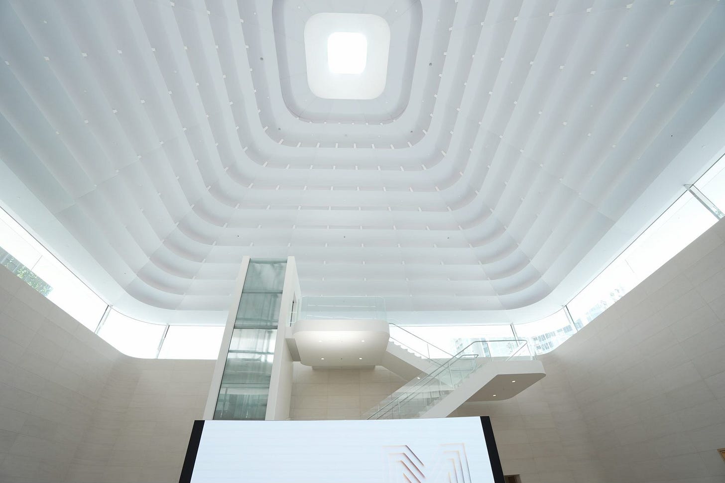 The oculus and elevator shaft of Apple The Exchange TRX during bright midday light. The oculus and elevator shaft of Apple The Exchange TRX during bright midday light.