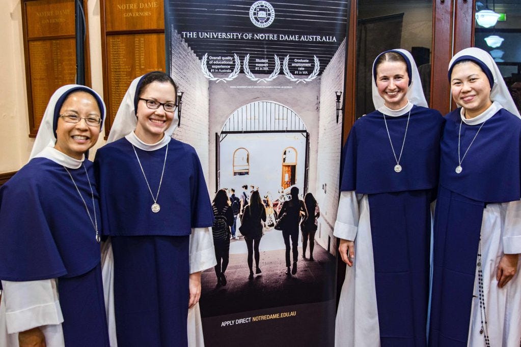 Four Sisters of Lilfe standing on by a banner.