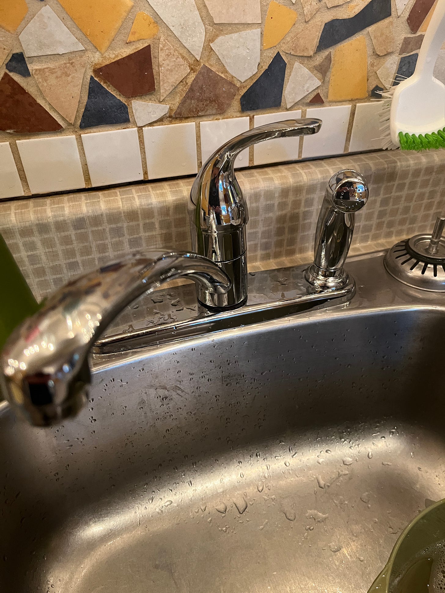 My kitchen faucet with one of those pull-out sprayers on the right hand side. The tiling on the back-splash is particularly lovely and colourful and a nice gift to the house from a former owner.