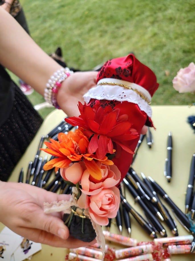 Plastic bottle maraca covered in lace, red silk and silk flowers.