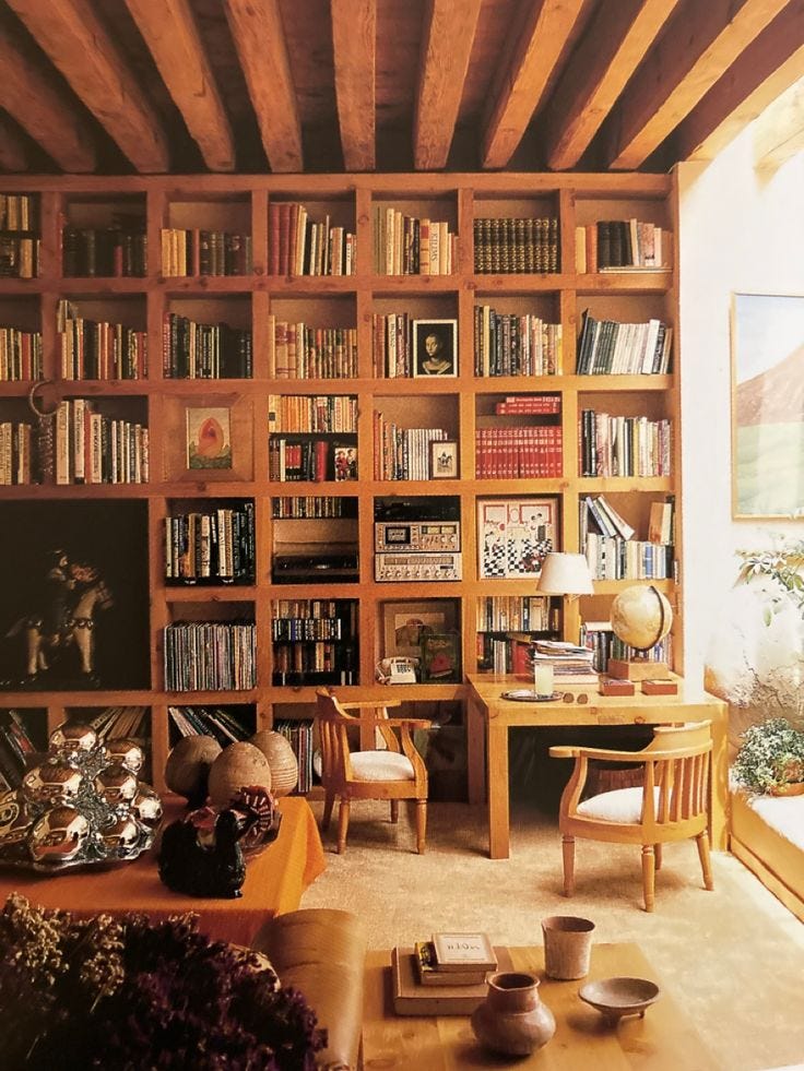 This may contain: a living room filled with lots of wooden furniture and bookshelves full of books