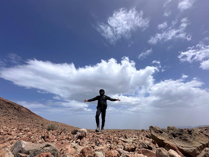 A person sitting alone on a volcanic rock at Montana Blanca, pausing to take in the landscape during a solo hike.