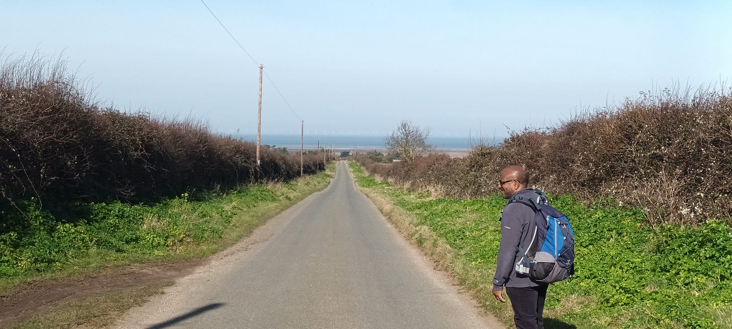 A lane leading down to the sea, a black man standing in the road