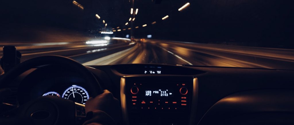 Driving in a car at night with blurred streetlights flying by