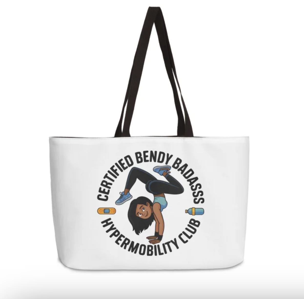 White tote bag with a black strap featuring a cartoon illustration of a woman doing a handstand with her legs extended upward. Encircling the illustration is the text ‘Certified Bendy Badass, Hypermobility Club.’ The design has a playful, bold style.