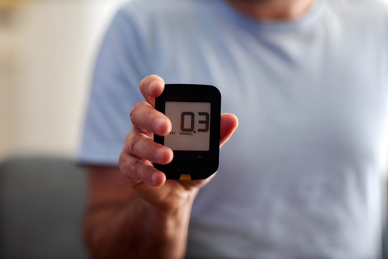 Person holding a ketone meter reading 0.3 mmol/L