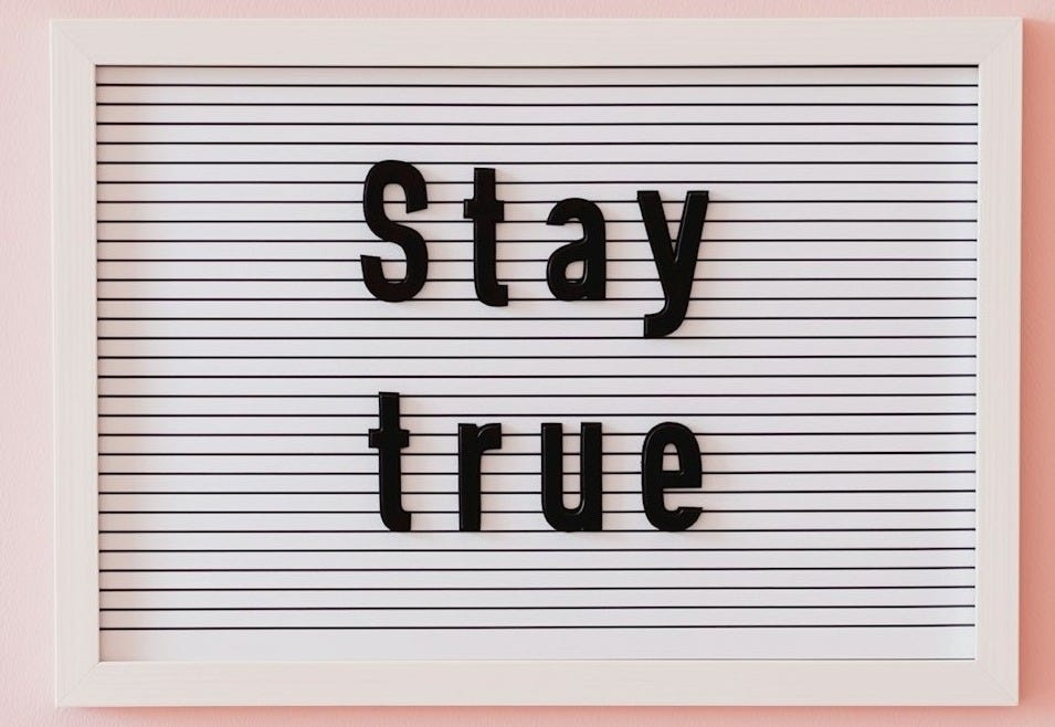 Letter board with "stay true" message on pink background