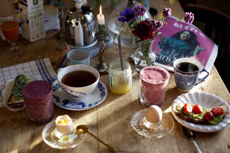 This may contain: a wooden table topped with plates and cups filled with food