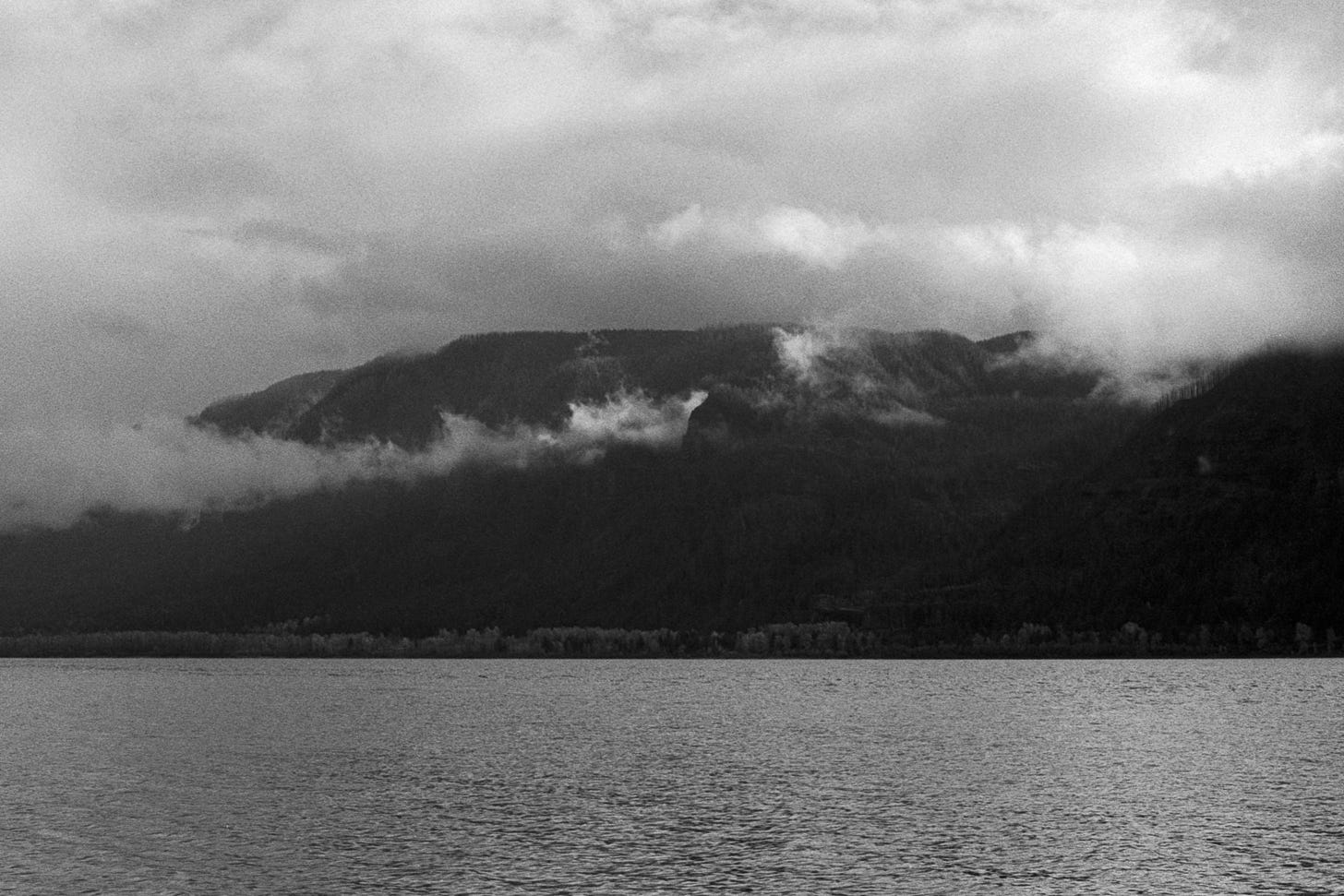A common pacific northwest view from the banks of the columbia river. Clouds sitting in the hillsides that make up the Columbia River Gorge