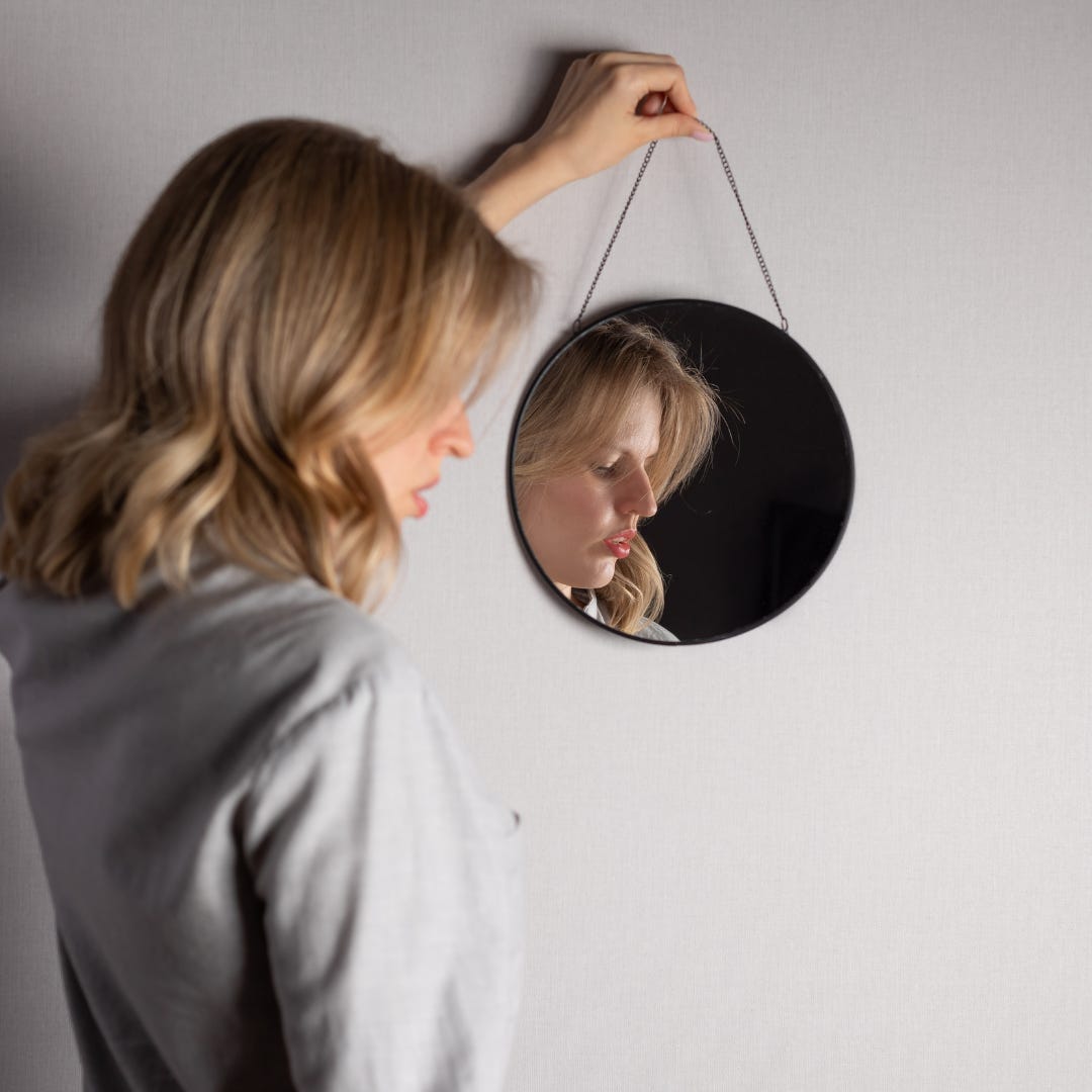 vrouw kijkt in spiegel pashokje sieraden kiezen moment voor zichzelf