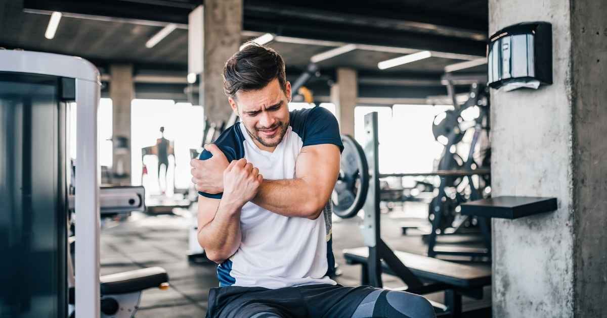 Man injured in the gym holding his shoulder 