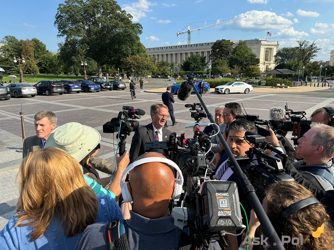 A politician surrounded by TV cameras answers questions 