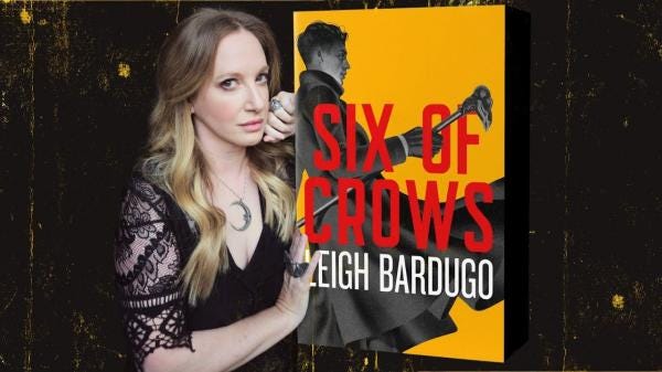 Leigh Bardugo stands next to Six of Crows a yellow book cover with a man on it.