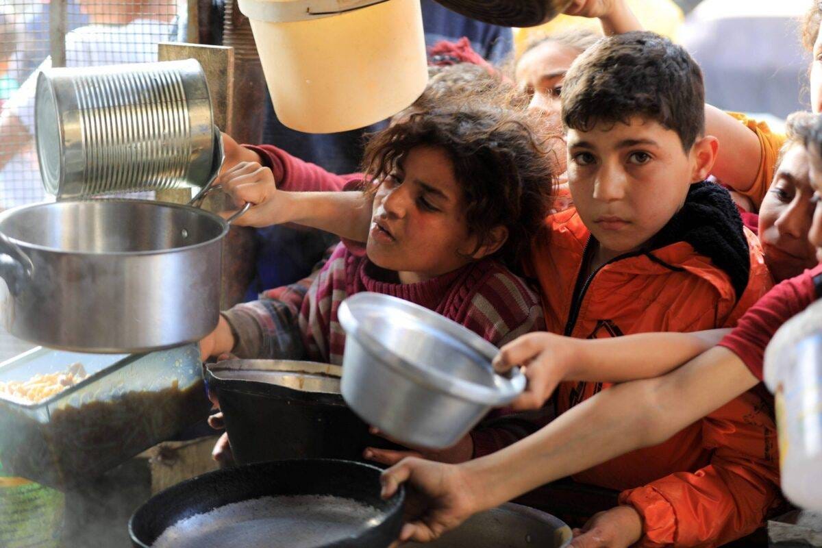 Palestinians hold empty containers to receive food, distributed by aid organisations, on the holy month of Ramadan as Israeli attacks continue Al- Shabura neighborhood, Rafah, Gaza on March 30, 2024 [Yasser Qudaih/Anadolu Agency]