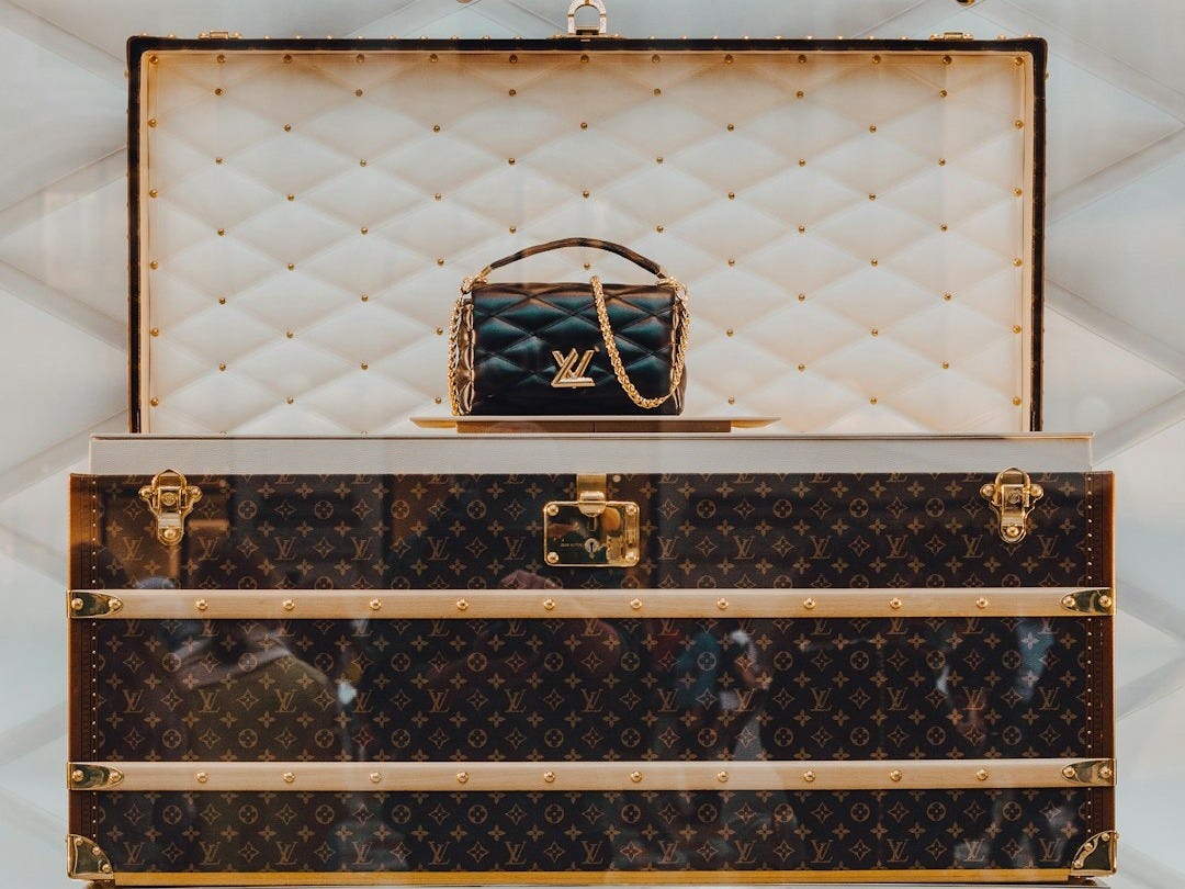 a louis vuitton trunk with a handbag on top of it