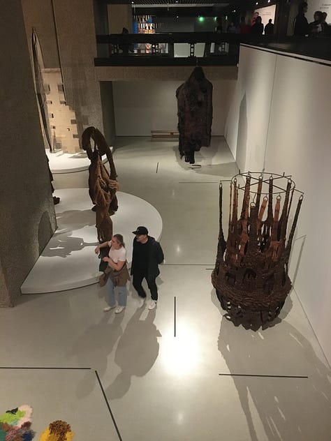 The exhibition viewed from the mezzanine showing large-scale works from — 1. Cecilia Vicuña (top) and Sarah Zapata (bottom); 2. Jagoda Buić (right) and Mrinalini Mukherjee (left); 3. Jeffrey Gibson.