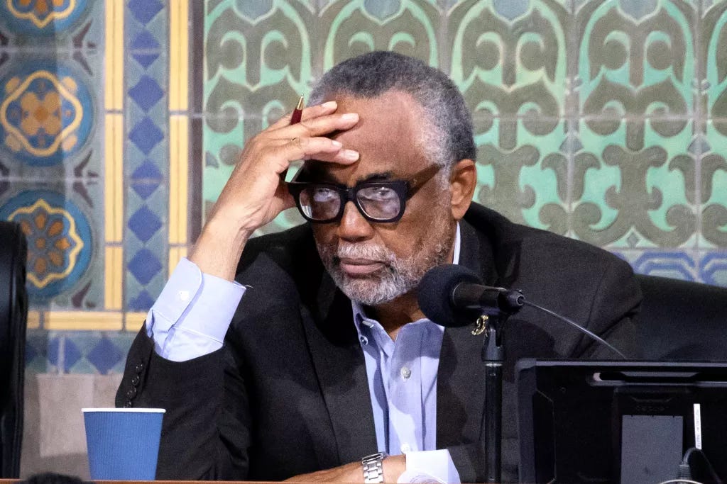 A man leans his forehead against his open right hand.