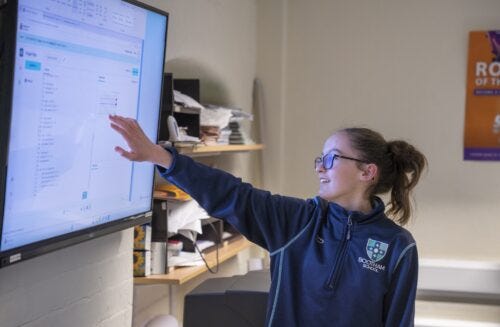 A young person presents her code on a large screen. A young person presents her code on a large screen.