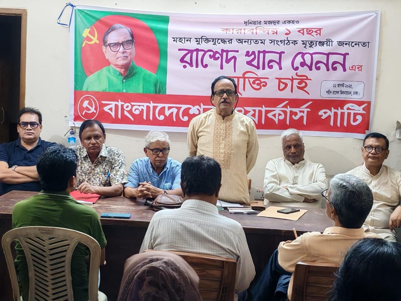 Bangladeshi activists and left leaders meet in front of a banner of Rashed Khan Menon