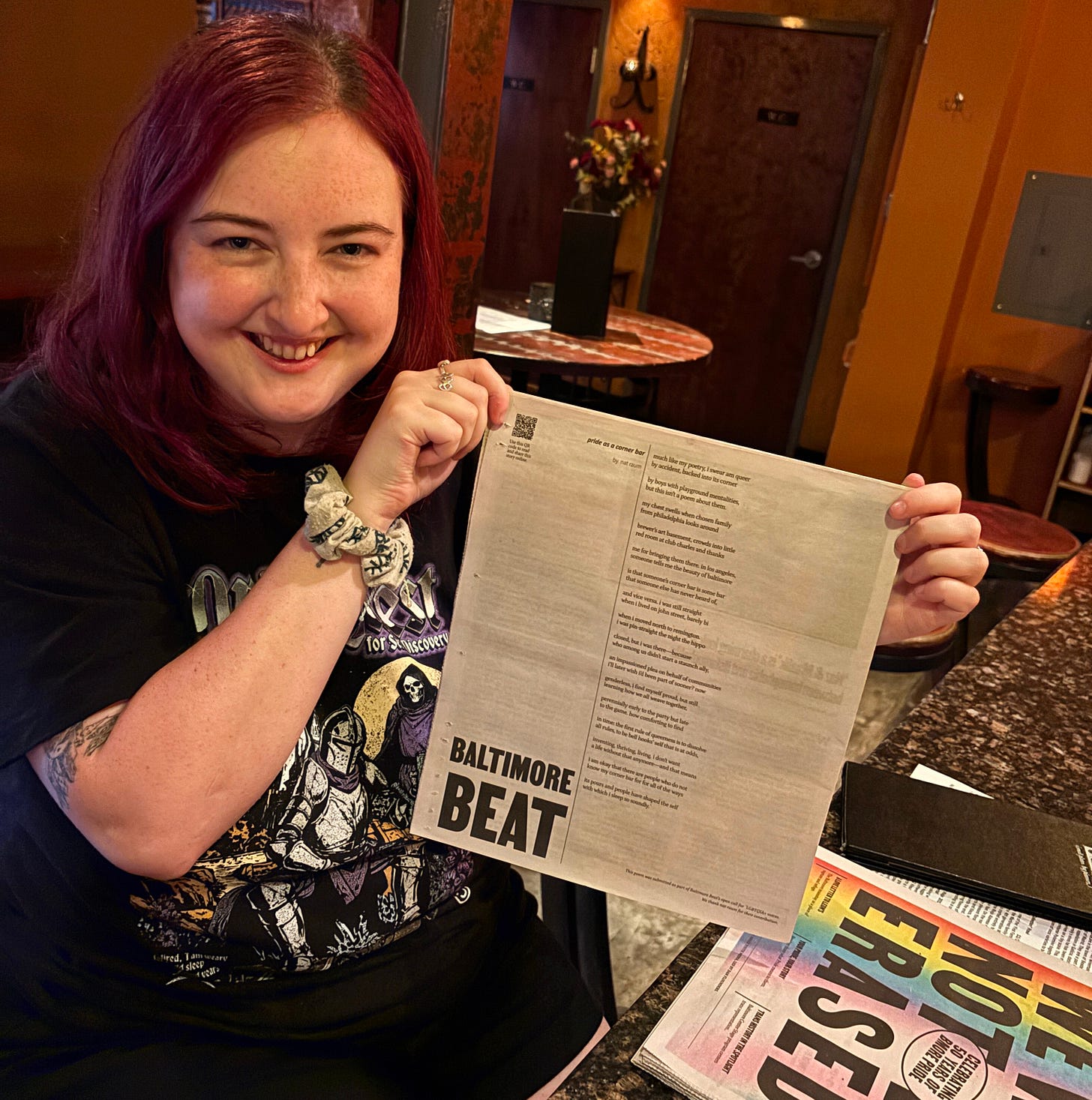 nat holding up their poem on the back cover of the Baltimore Beat pride issue