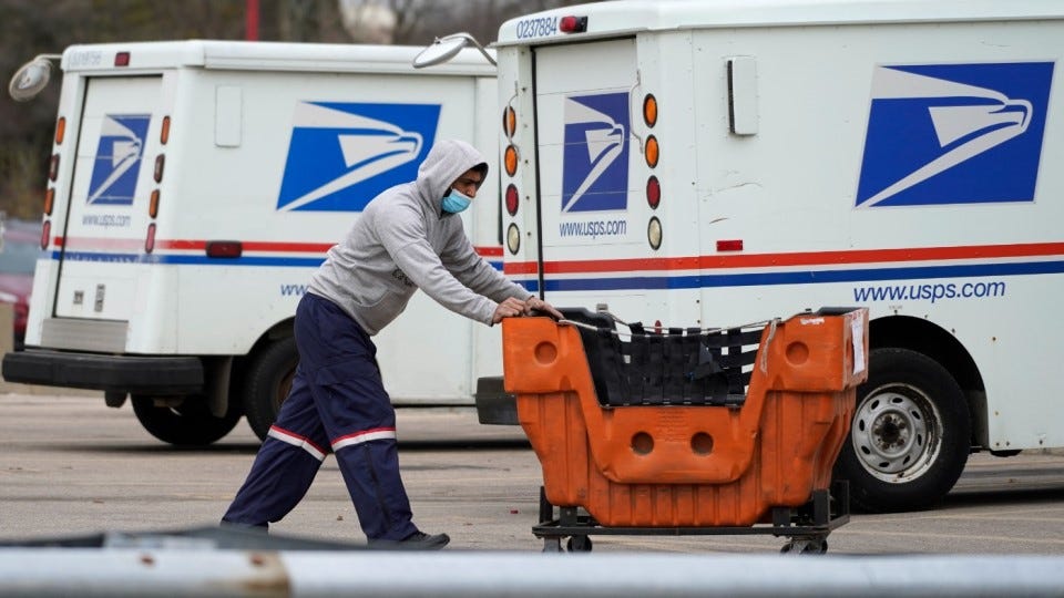 A U.S. Postal Service employee works outside a post office in Wheeling, Ill.