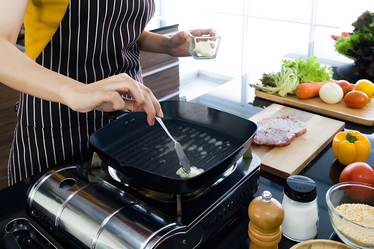 Person cooking meat and vegetables in butter